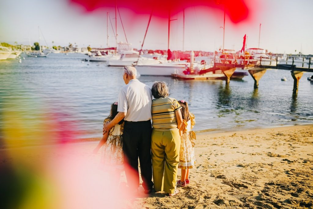 The best personal loans for pensioners are available at LendEasy. Retired couple walk with grandchildren on the beach in Australia.