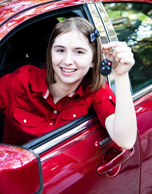A happy LendEasy customer in a red car holding the keys and smiling as she was approved for a car loan with our help.