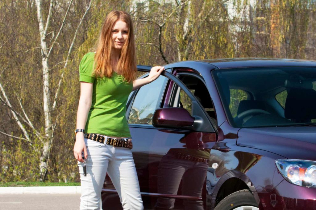 Car loans for ABN holders are available at LendEasy. Redheaded girl stands next to a new car.