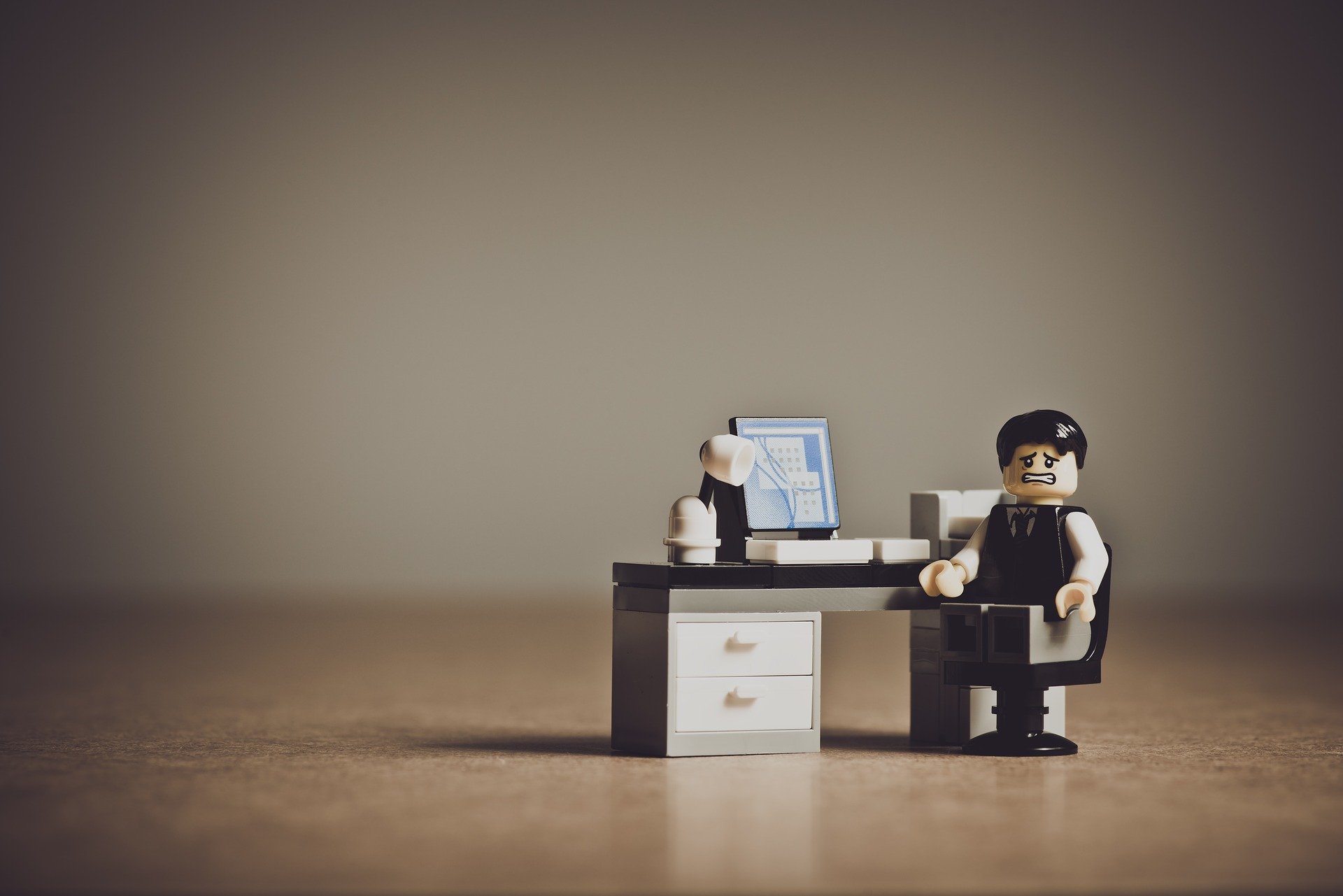 Small loans can turn your life around. A Lego business man sits at a tiny desk with a lamp and laptop.