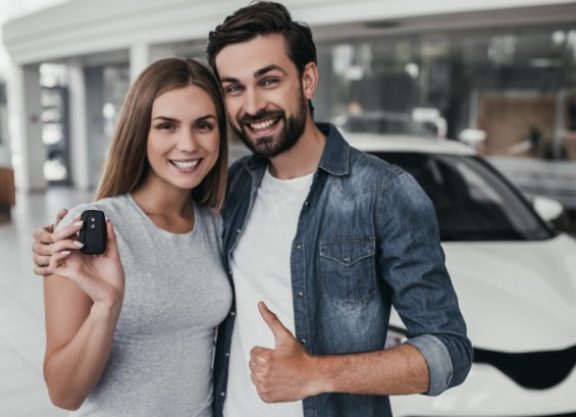 Happy car owners holding the keys to their car