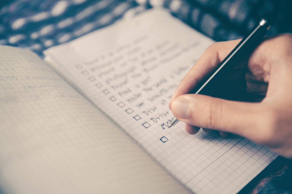 Don't stress your personal loan eligibility check. A hand writing a checklist in a notebook with a black pen.
