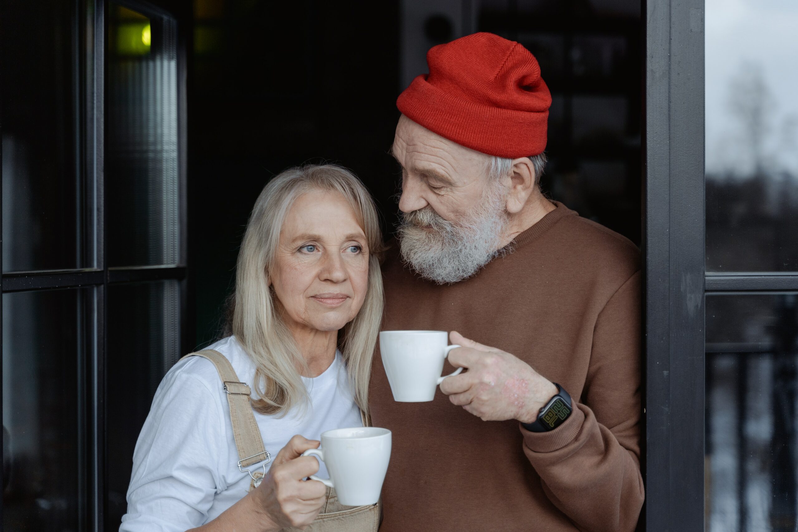 Retirement in Australia requires careful planning. A retired couple stand together with cups of coffee considering their finances.